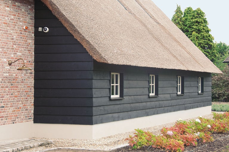 Gebouw met rieten dak, houten gevelbekleding, beveiligingscamera en buitenverlichting