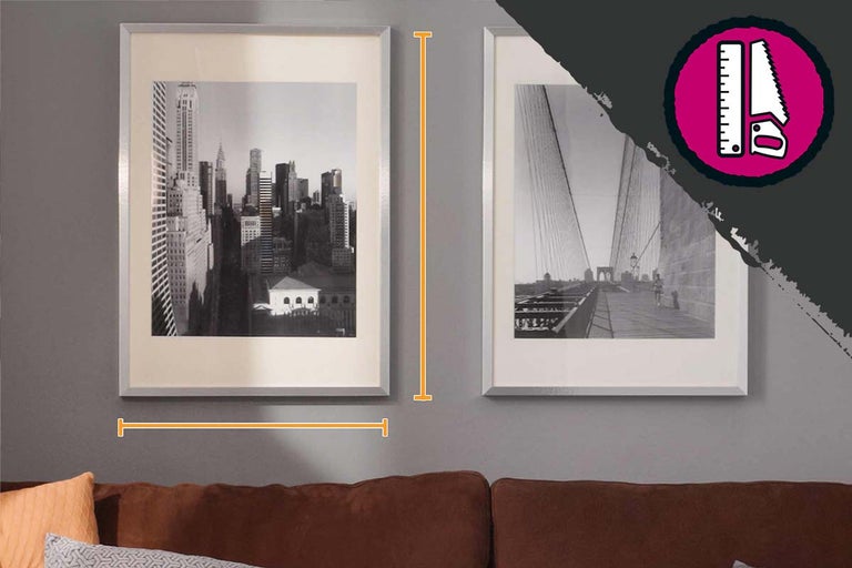 Twee ingelijste zwart-witfoto's hangen aan een muur boven een bank. De linker foto toont een stadsgezicht, de rechter foto toont een brug.