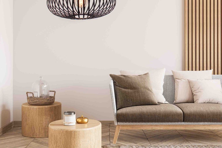 Decoratieve woonkamer met een hanglamp boven een bank, bijzettafels en woonaccessoires.