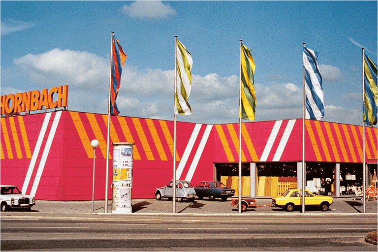 Hornbach bouwmarktgevel met vlaggen en geparkeerde auto's