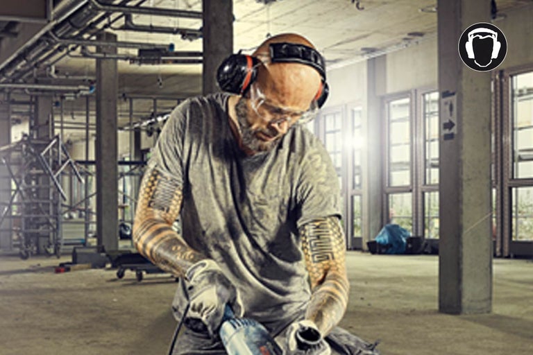 Ambachtsman met veiligheidsbril en gehoorbescherming aan het werk in een werkplaats. Symbool gehoorbescherming verplicht.