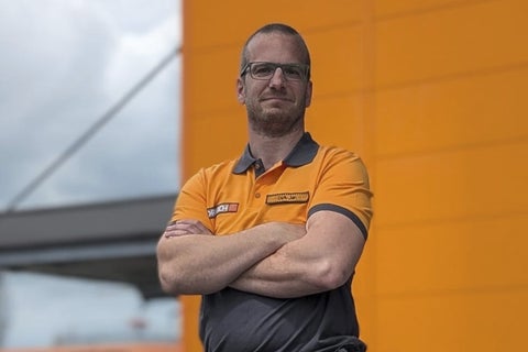 Een Hornbach medewerker met gekruiste armen voor een wand.