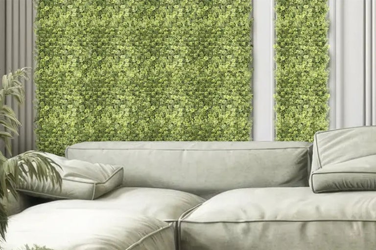 Decoratieve groene plantenwand achter een bank in de woonkamer.