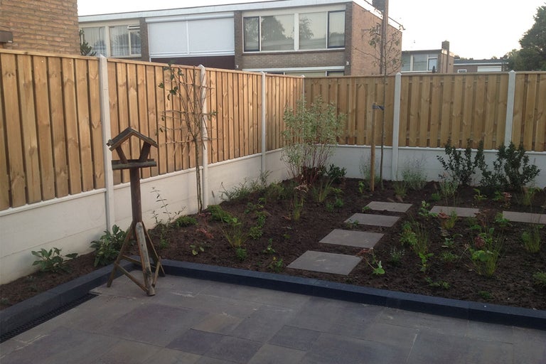 Tuin met houten schutting en looptegels
