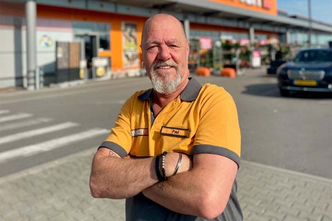 Hornbach medewerker genaamd Paul staat glimlachend met gekruiste armen voor een Hornbach bouwmarkt.