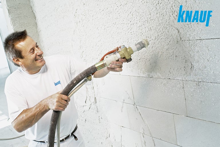 Ambachtsman brengt gips aan met een gipsmachine op een muur. Knauf Logo.