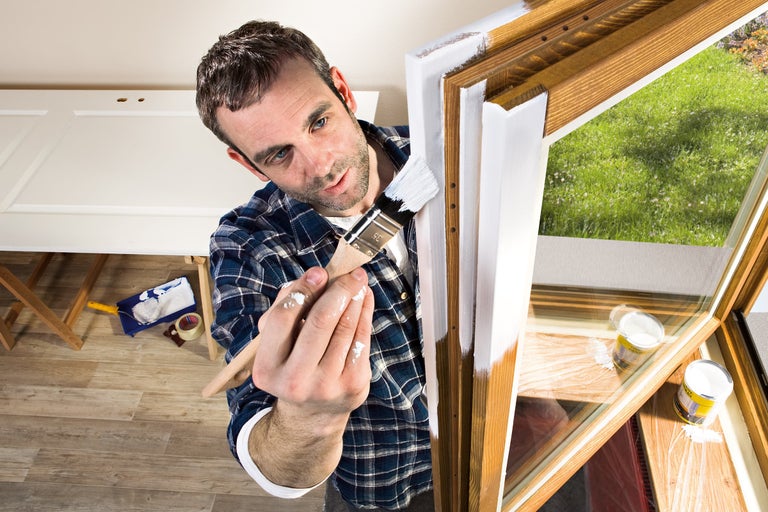 Man schildert houten raam met een penseel