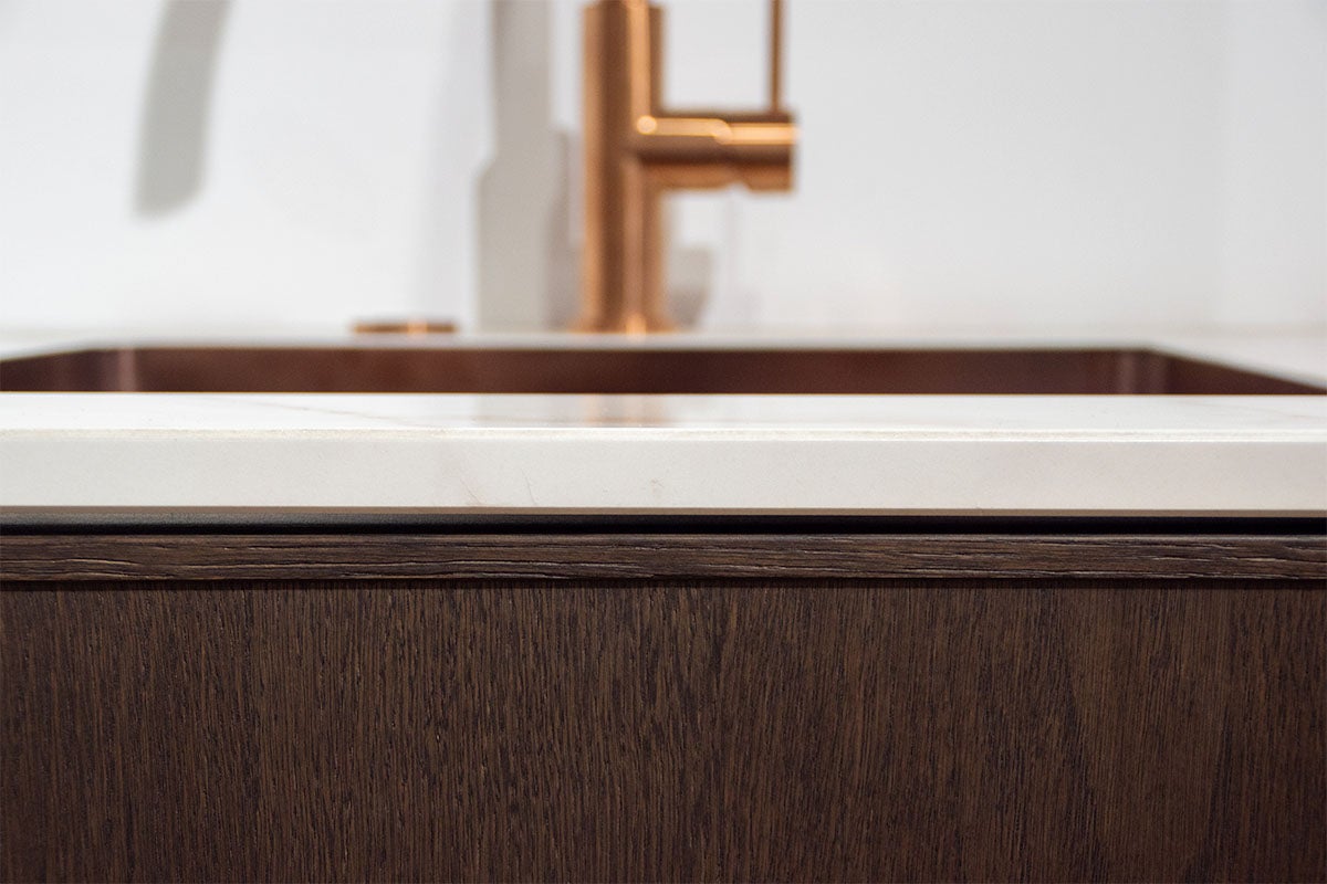 Detailopname van een badkamer met wastafelonderkast, wastafel en kraan.