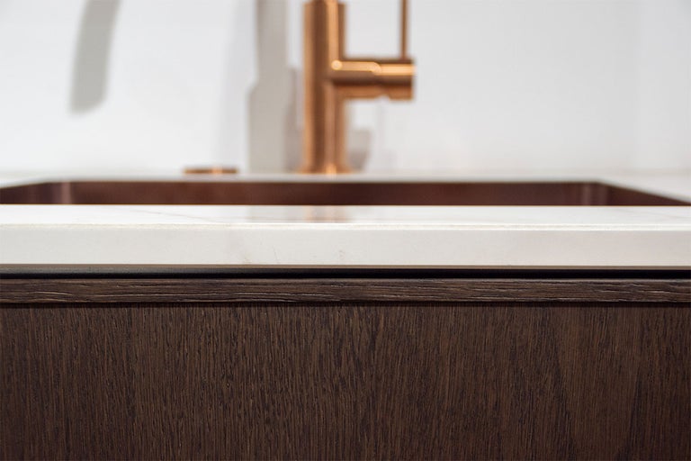 Detailopname van een badkamer met wastafelonderkast, wastafel en kraan.