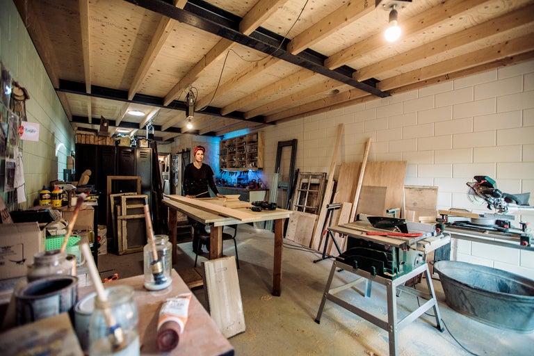 Werkplaats met gereedschap, houten tafel en een vrouw