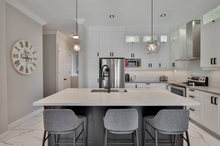 Lichte keuken met kookeiland, barkrukken, keukenapparatuur en verlichting