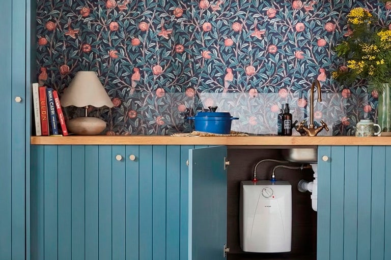 Keukenscène met blauwe onderkast, spoelbak, kraan, kookpot, close-in boiler en bloemenbehang