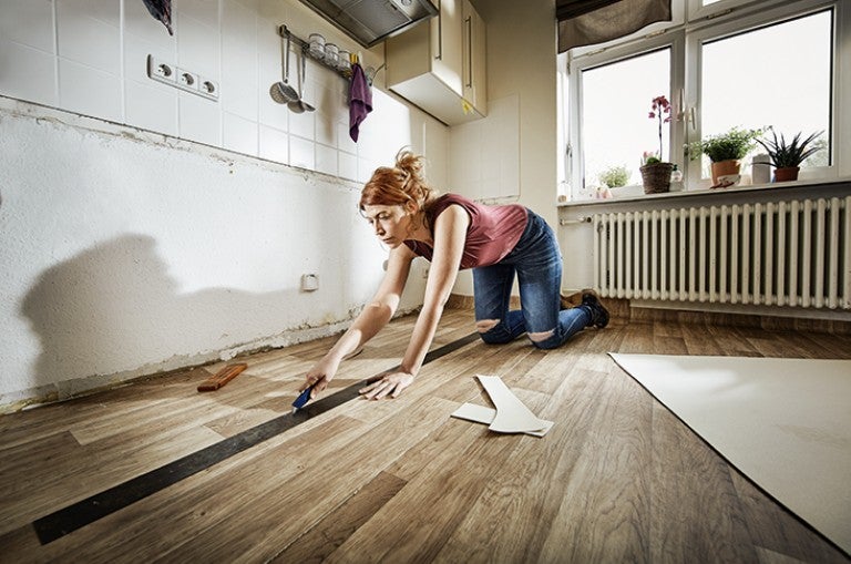 Vrouw snijdt vinylvloer in een keuken