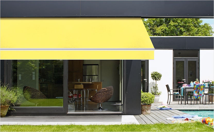Geel zonnescherm aan een modern huis met terras en zwembad.
