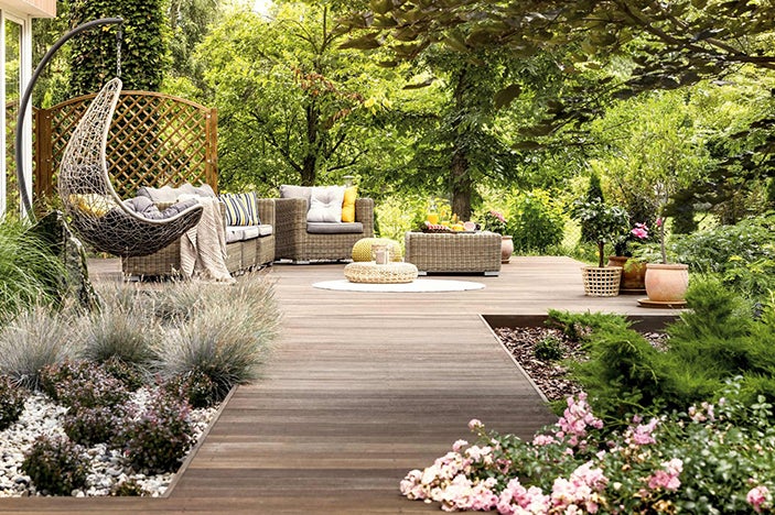 Houten terras met tuinmeubelen zoals hangstoel, bank, tafel en planten