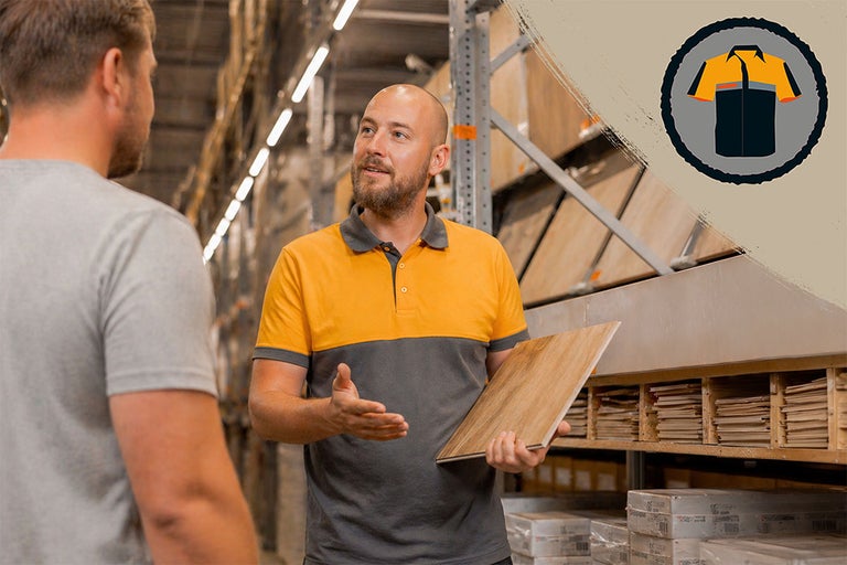Hornbach medewerker geeft deskundig advies over vloeren en laat een klant een laminaatstaal zien bij stellingen met monsters.