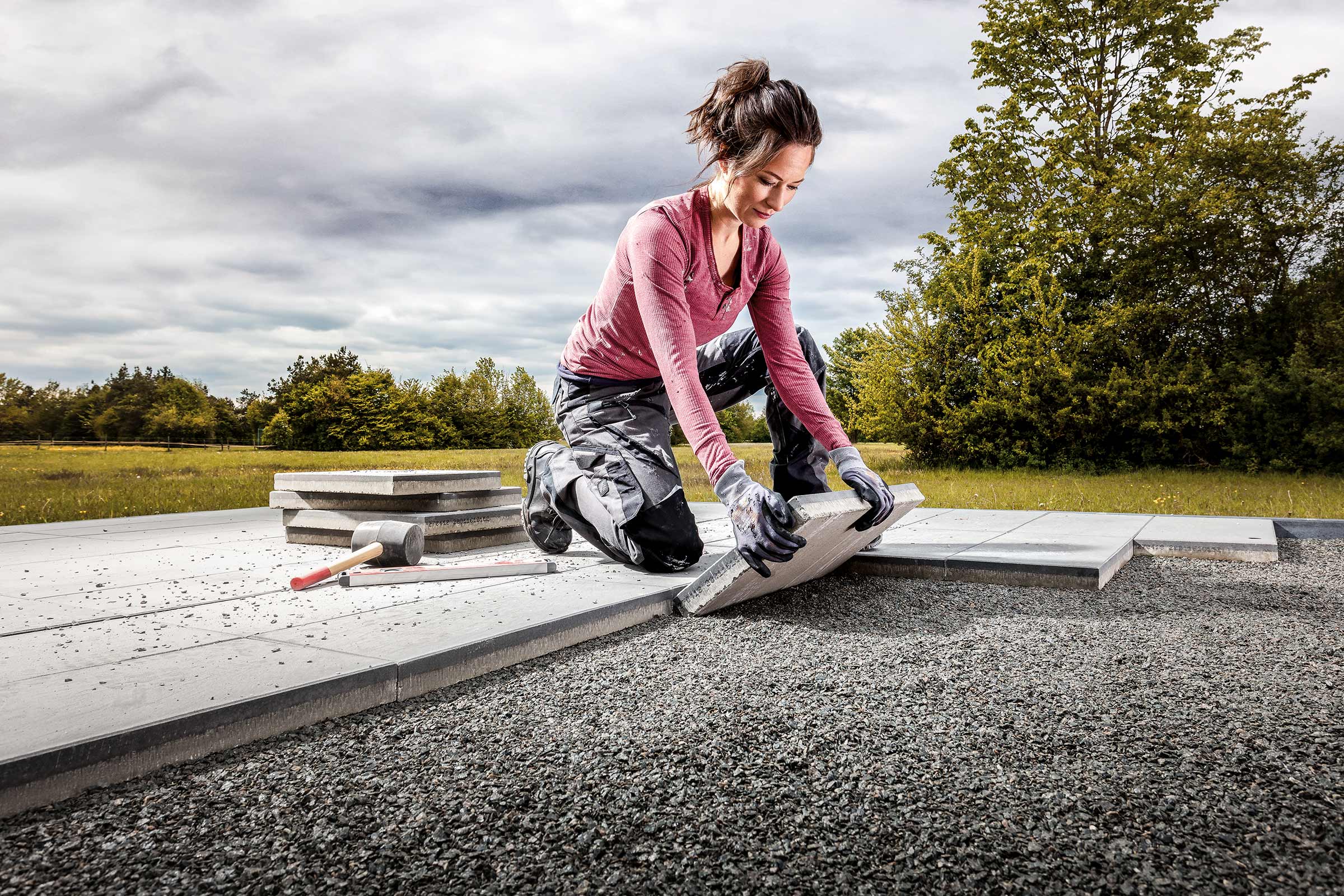 Vrouw legt betontegels in de tuin