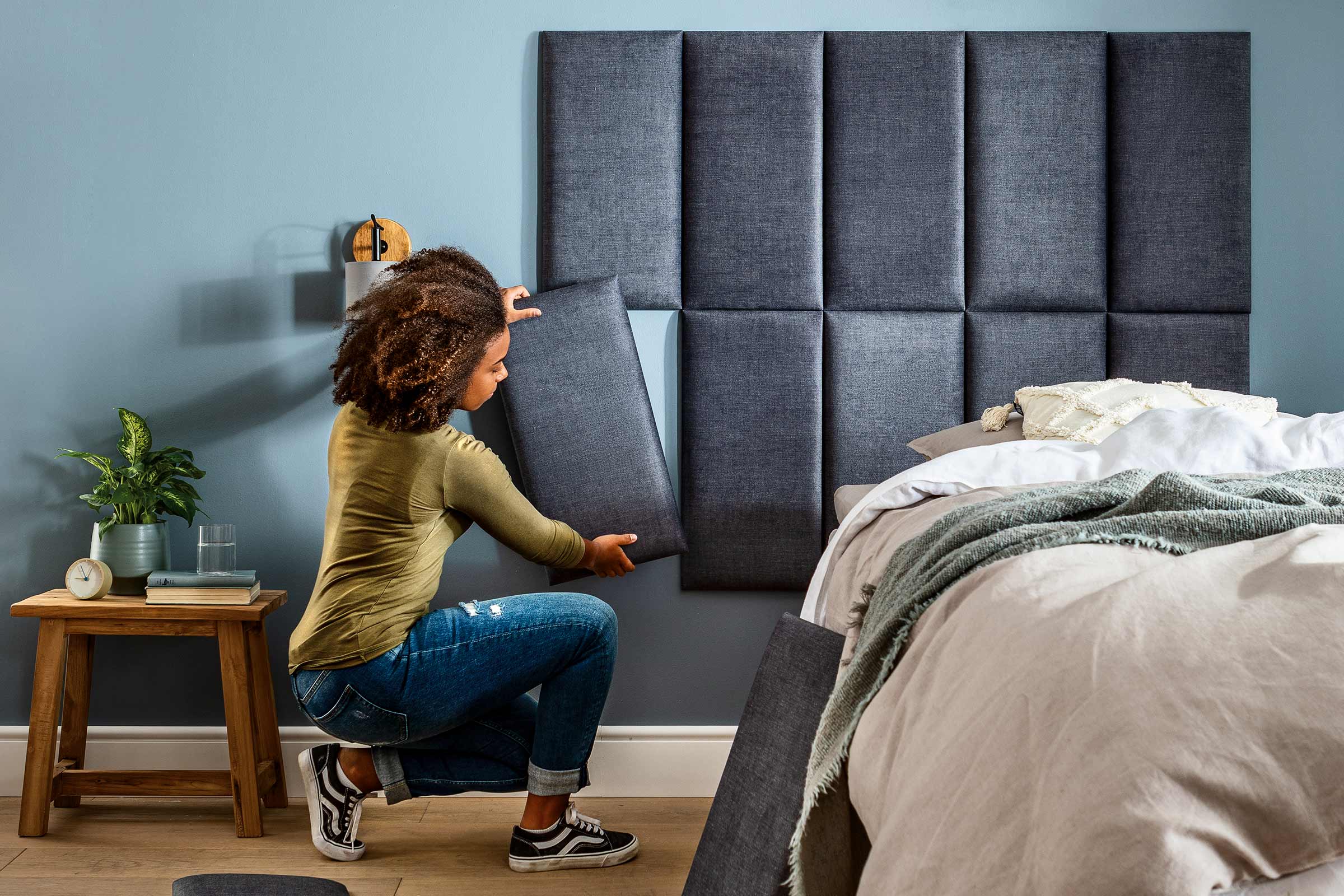 Vrouw bevestigt een wandpaneel als hoofdeinde in de slaapkamer