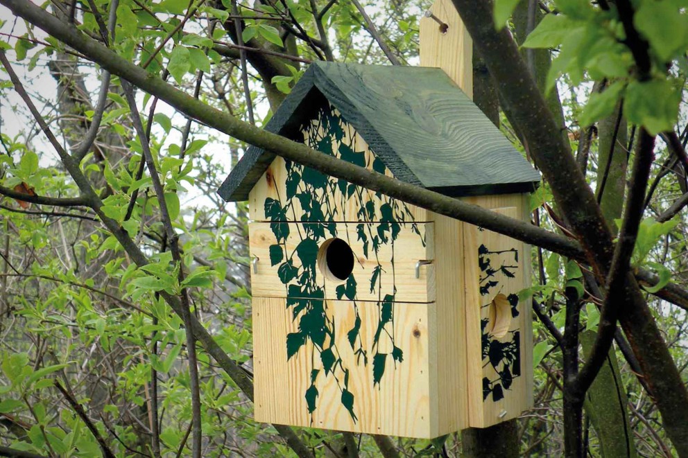 Houten vogelhuis met klimopmotief in een boom