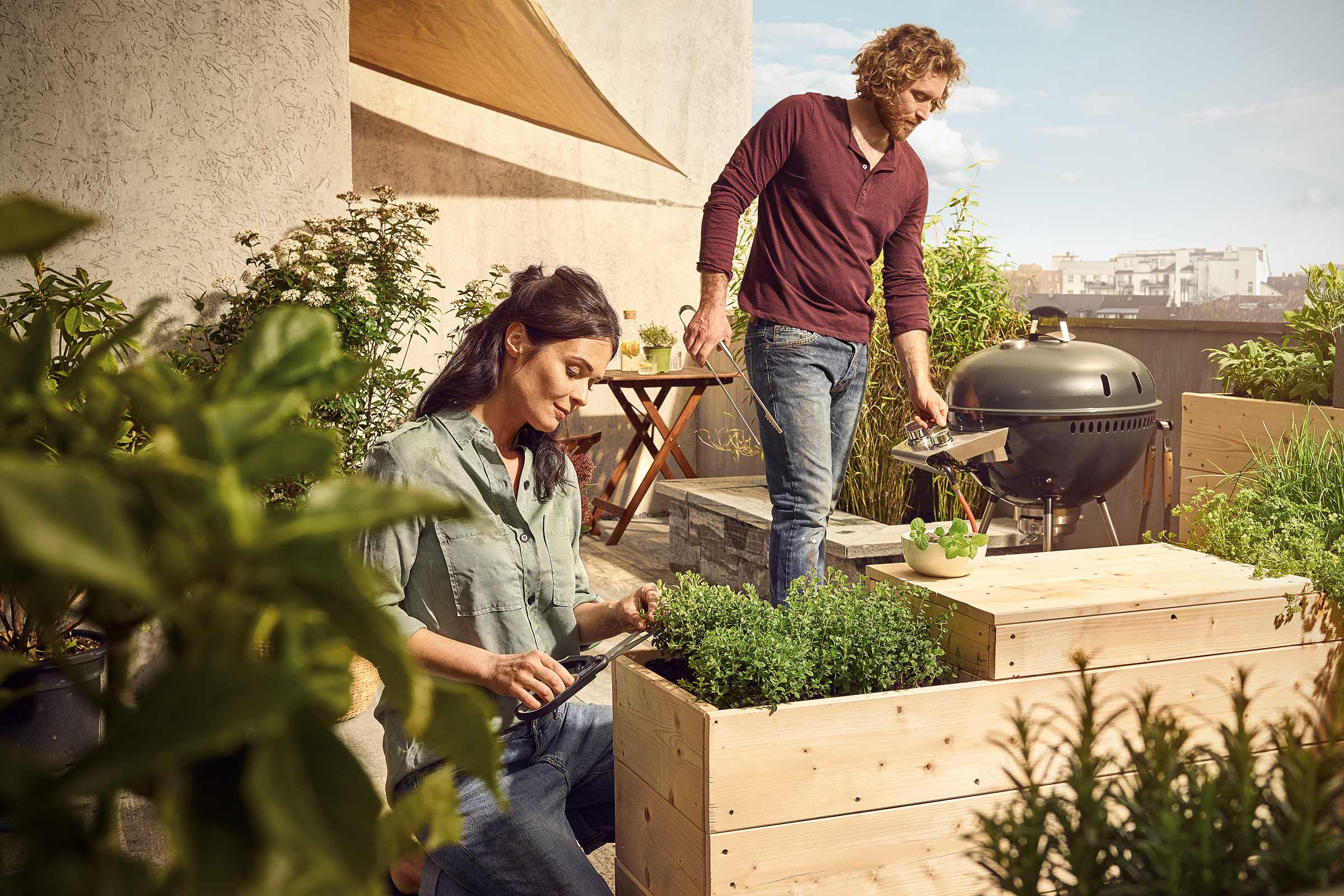 Mensen tuinieren en barbecueën op een dakterras met verhoogde plantenbakken en een barbecue