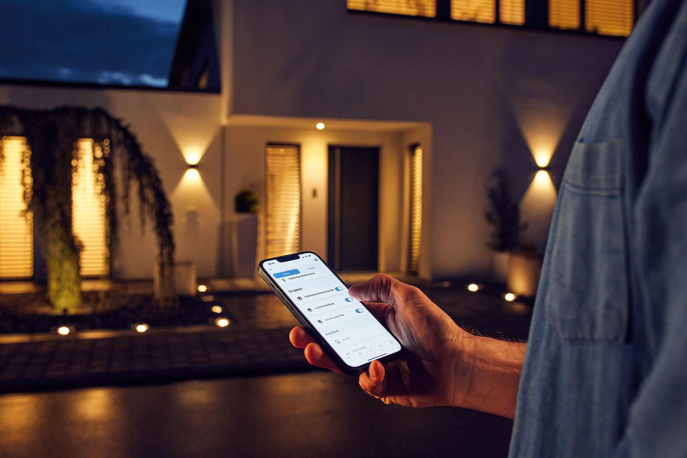 Persoon bedient buitenverlichting met smartphone app bij het huis