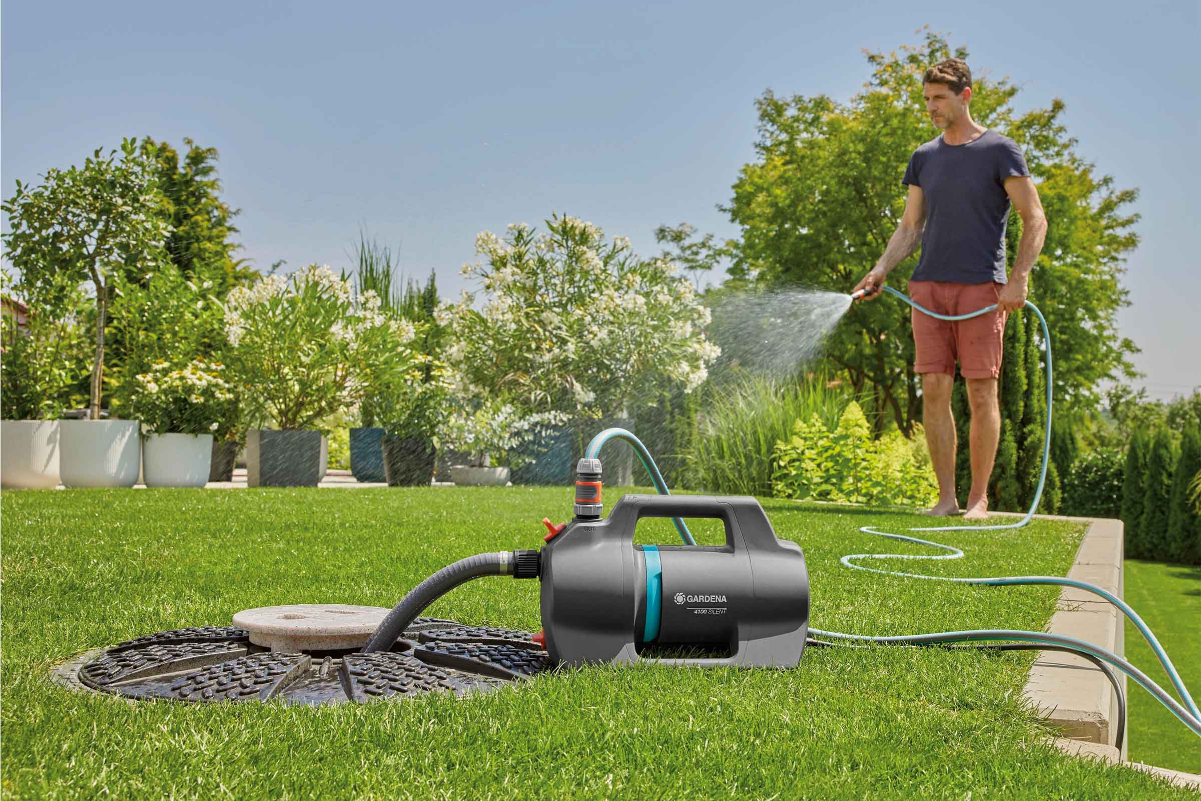 Tuinscène met man die planten water geeft met een Gardena tuinpomp