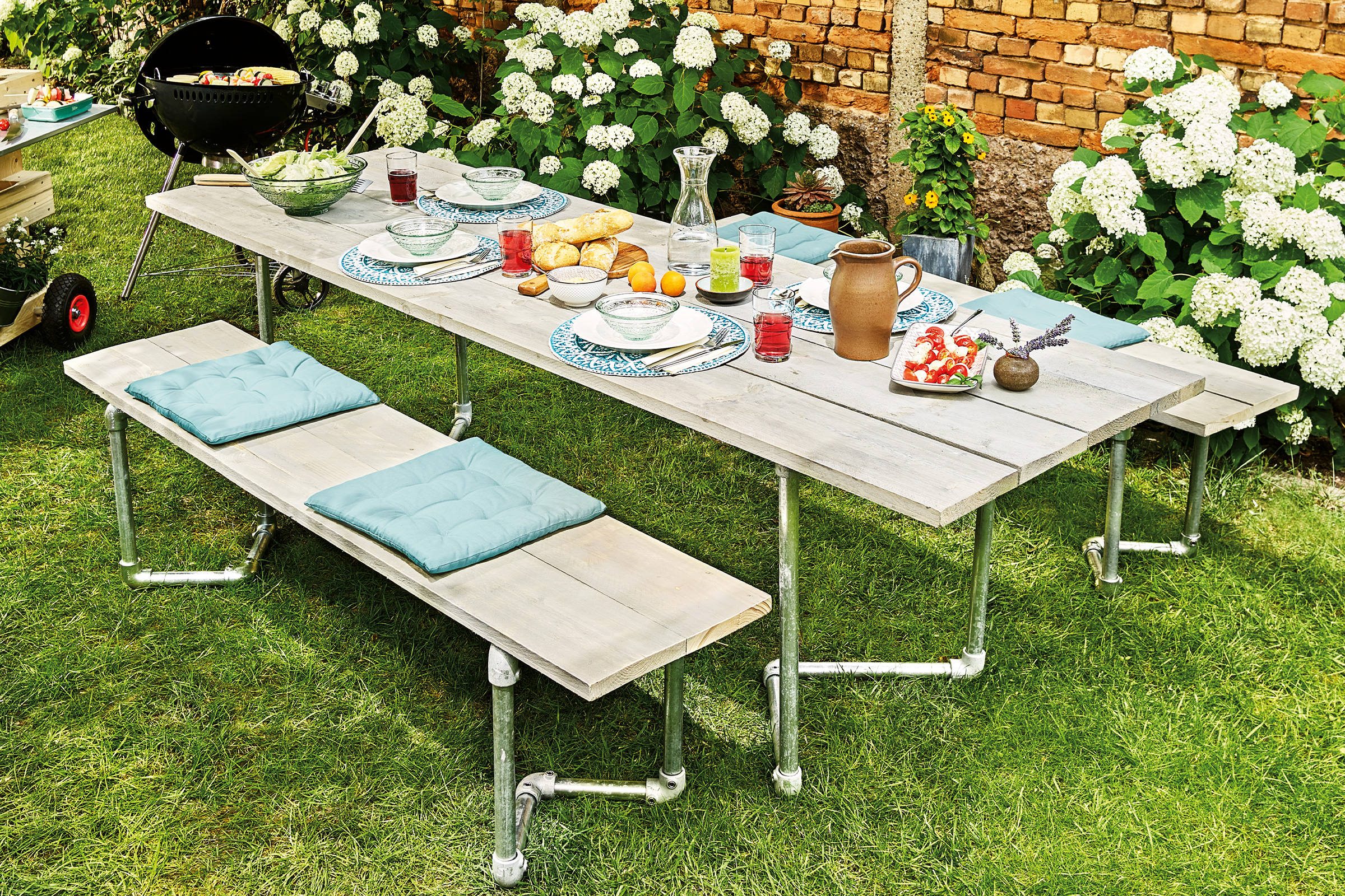 Gedekte eettafel en banken in de tuin met barbecue