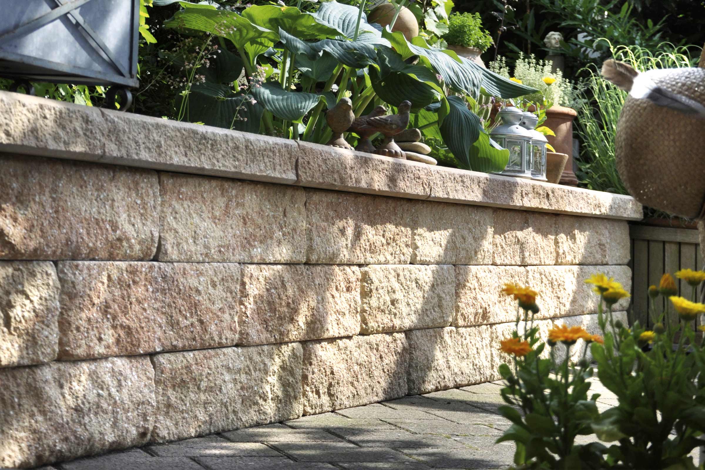 Een tuinmuur van natuursteen met planten en decoratieve elementen