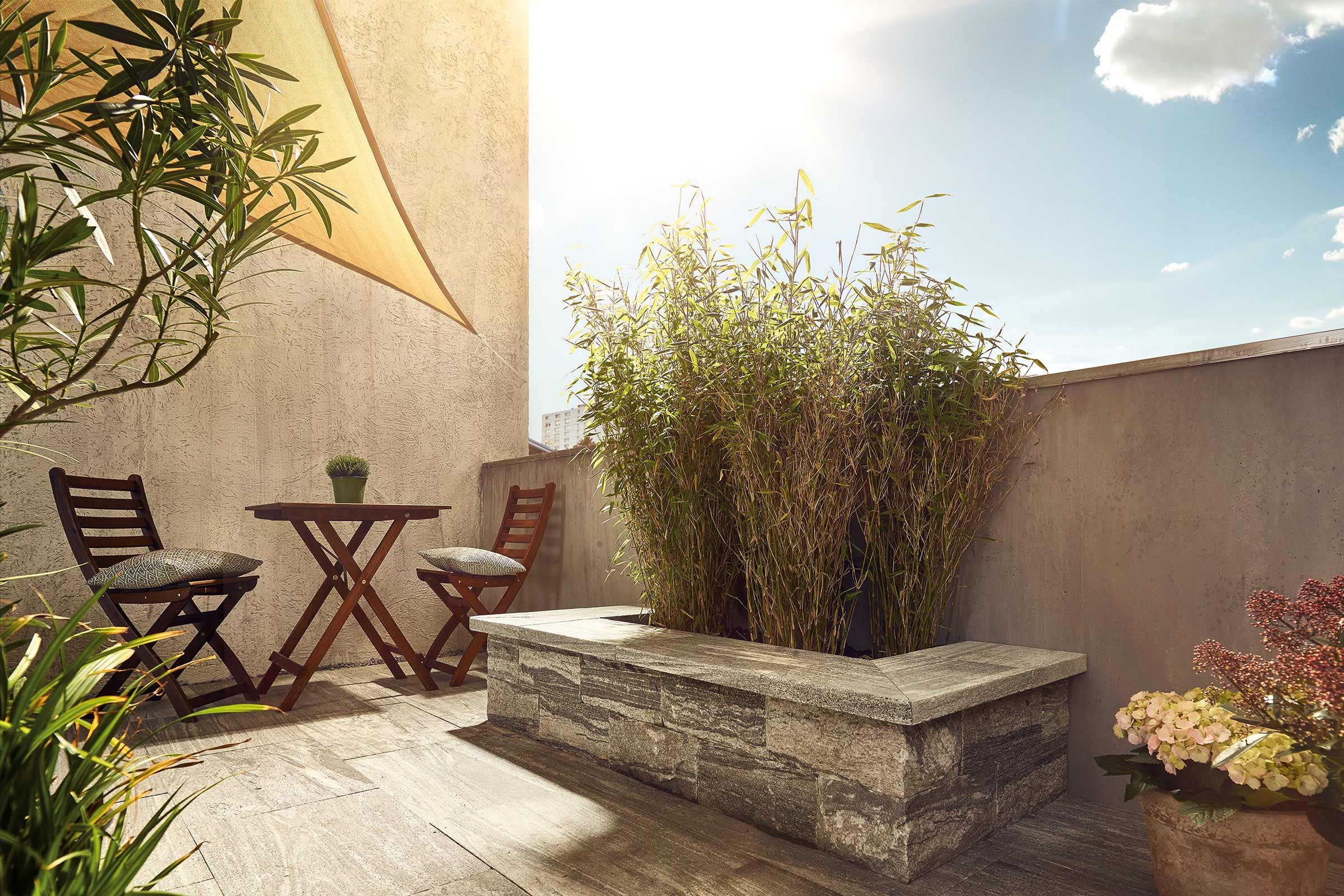 Terras met houten vloer, houten tafel met twee stoelen, bamboe en zonnescherm