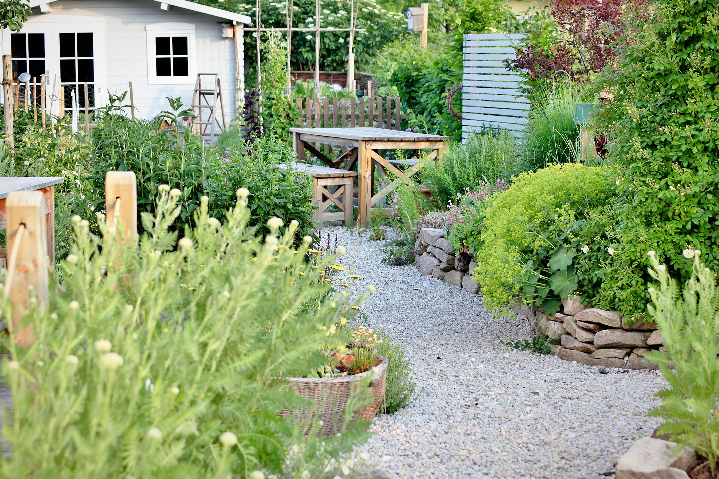 Tuin met tuinhuis, houten tafel en grindpad