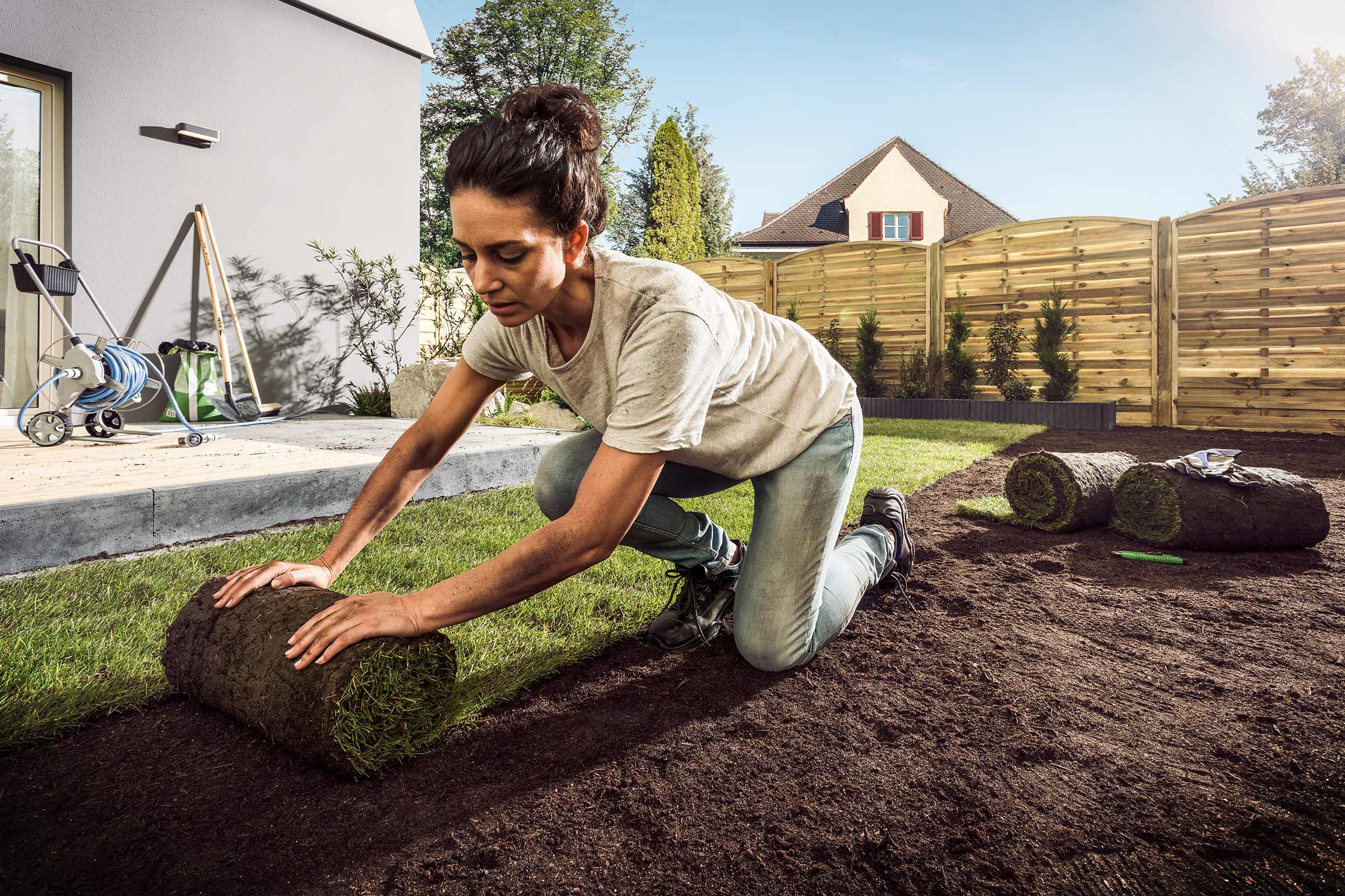 Vrouw legt grasrollen in de tuin.