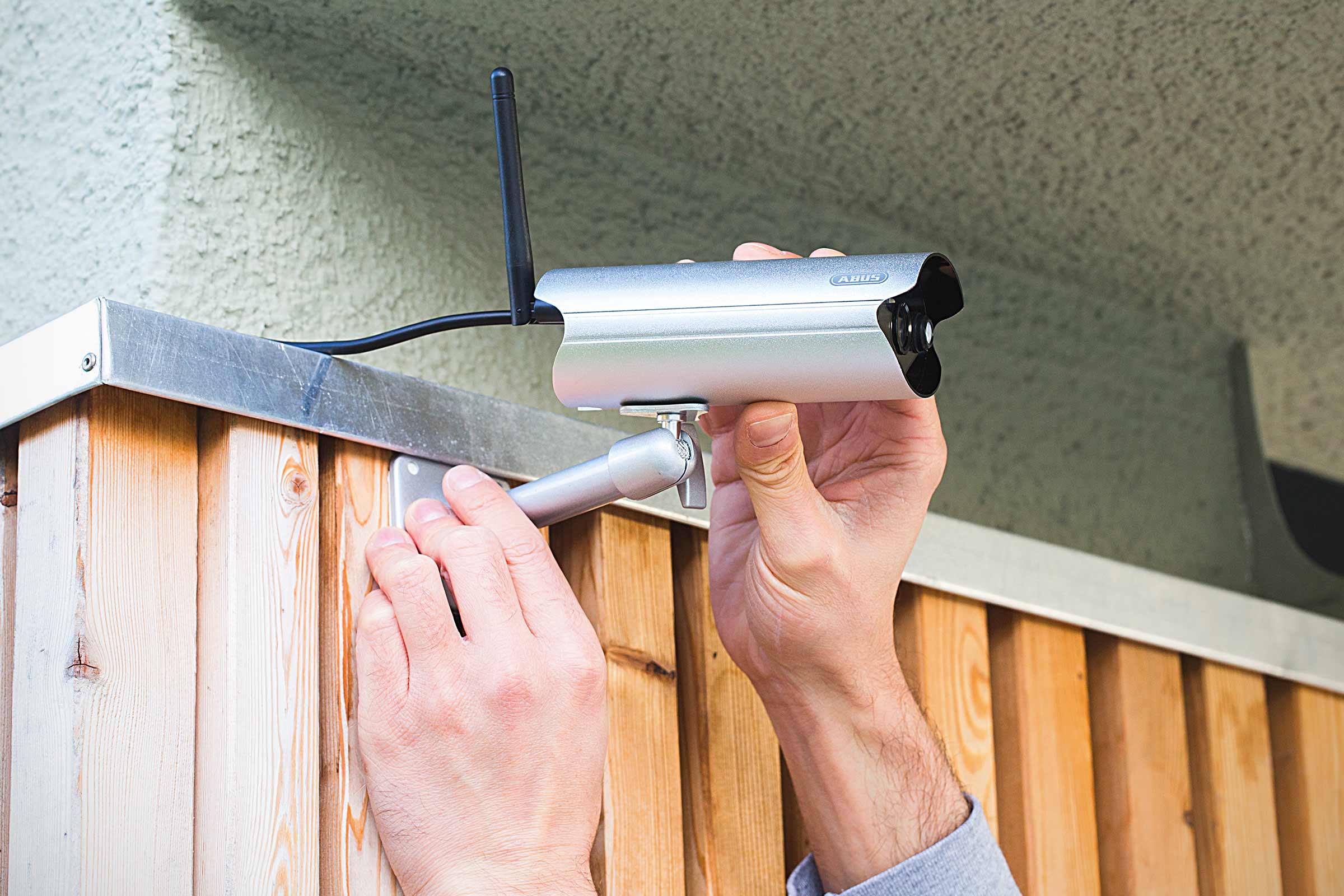 Installatie van een ABUS bewakingscamera met antenne op een houten muur