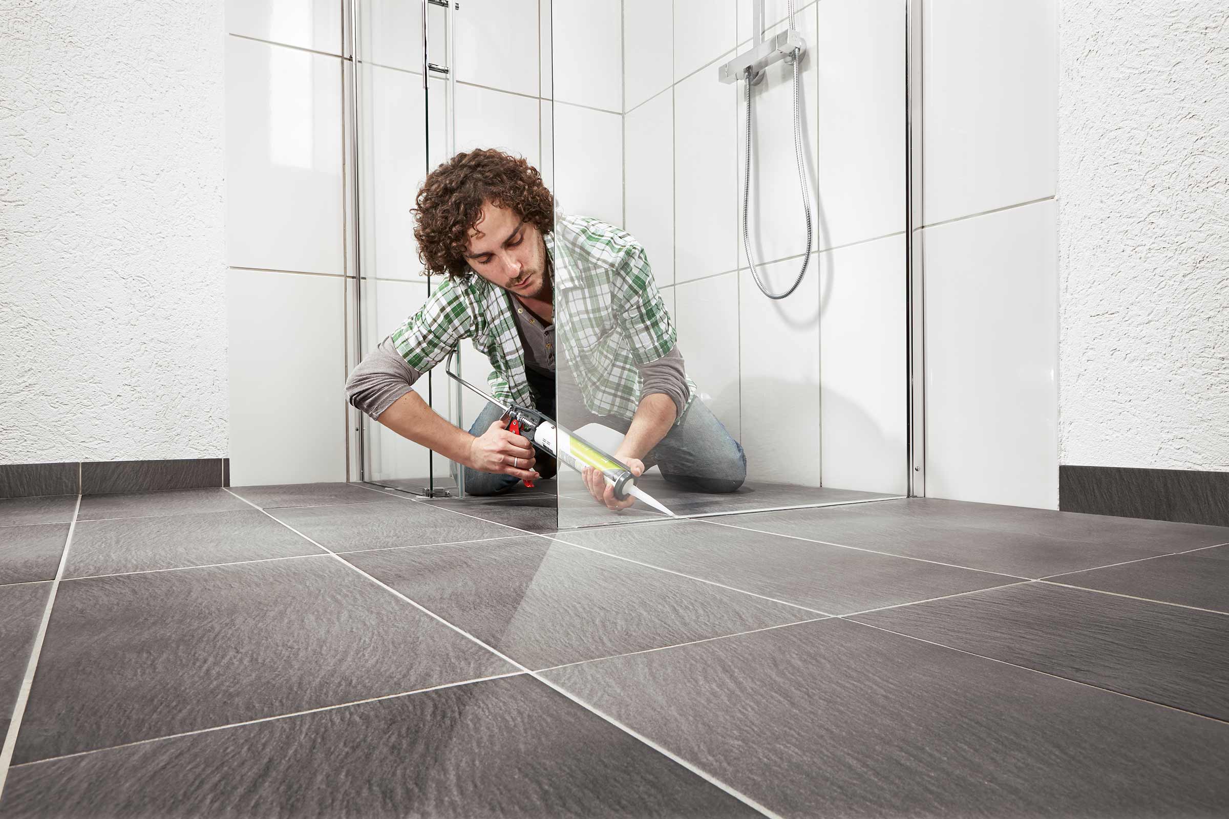 Man dicht douche af met kit en kitpistool in de badkamer.