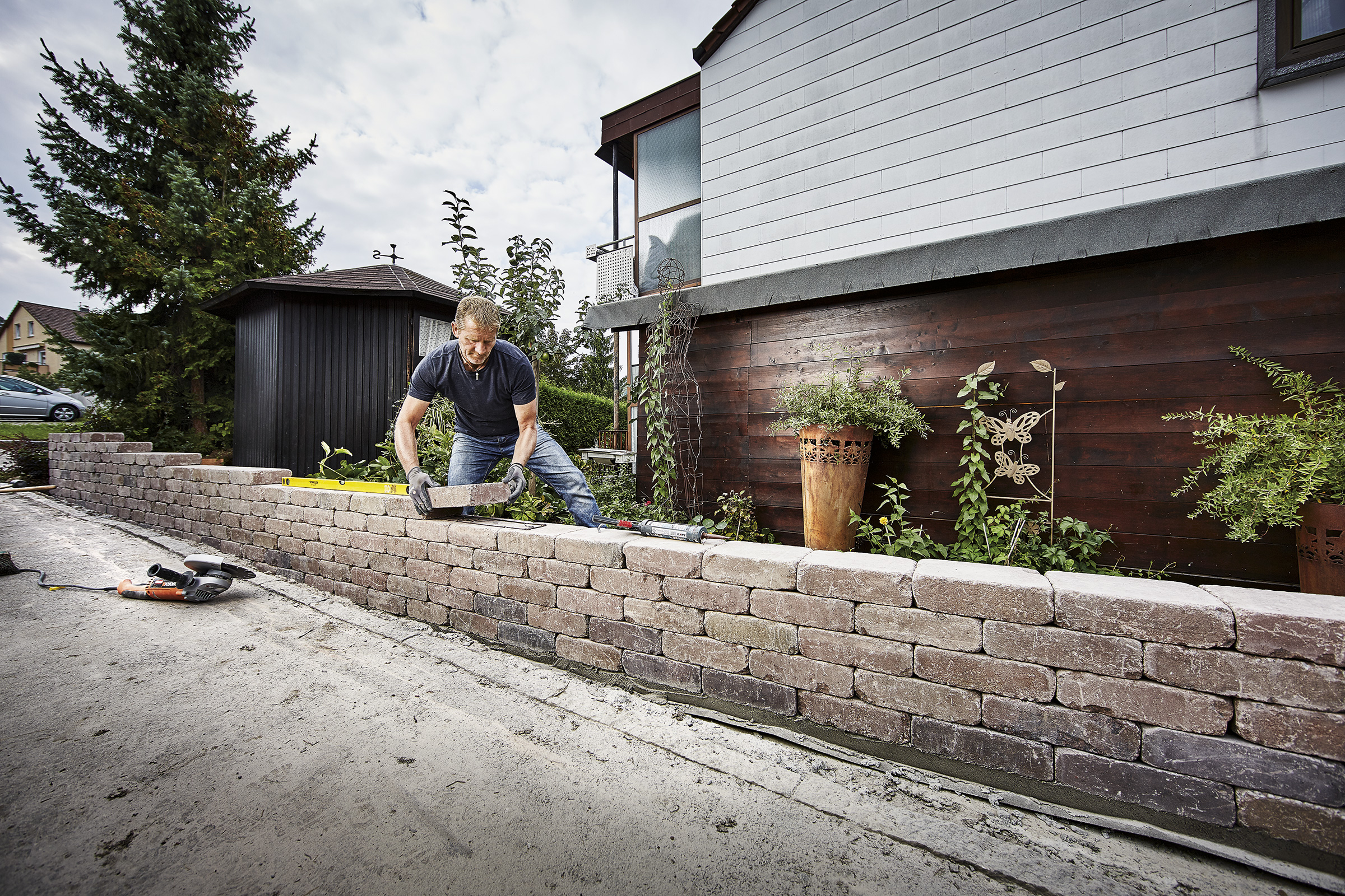 Man bouwt een muur van straatstenen in de tuin.