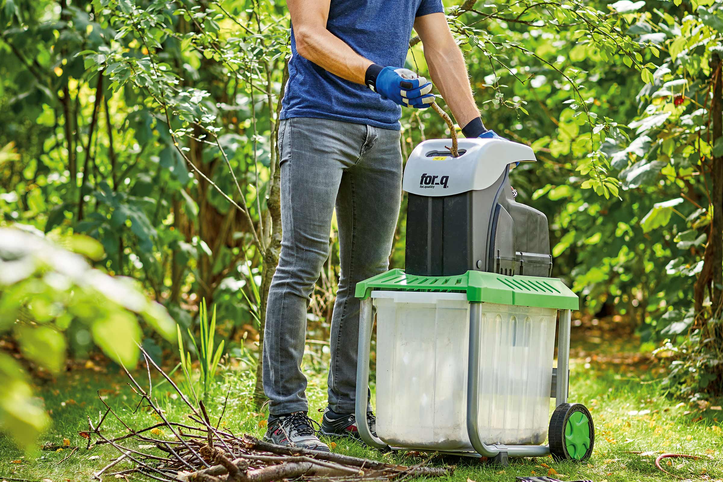 Man bedient een hakselaar in de tuin om takken te versnipperen