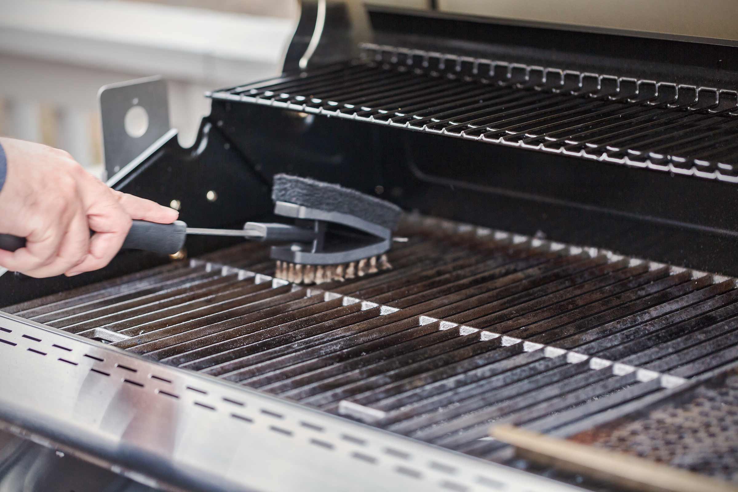 Een grillborstel reinigt een grillrooster.