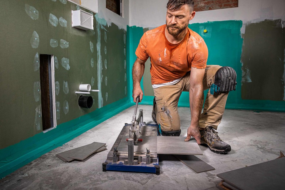 Tegelzetter aan het werk met tegelsnijder in badkamer