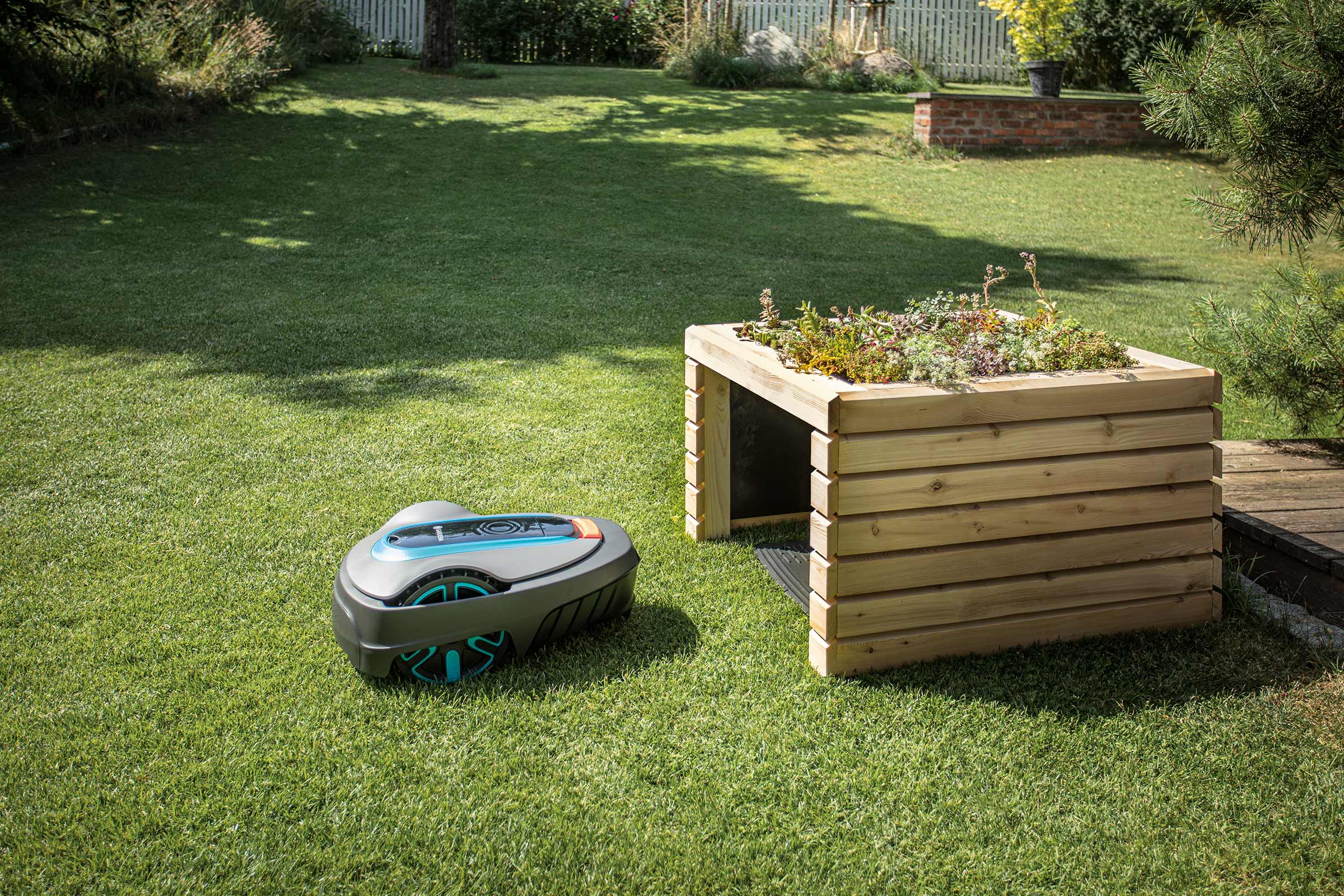 Tuinscene met robotmaaier en houten plantentafel.
