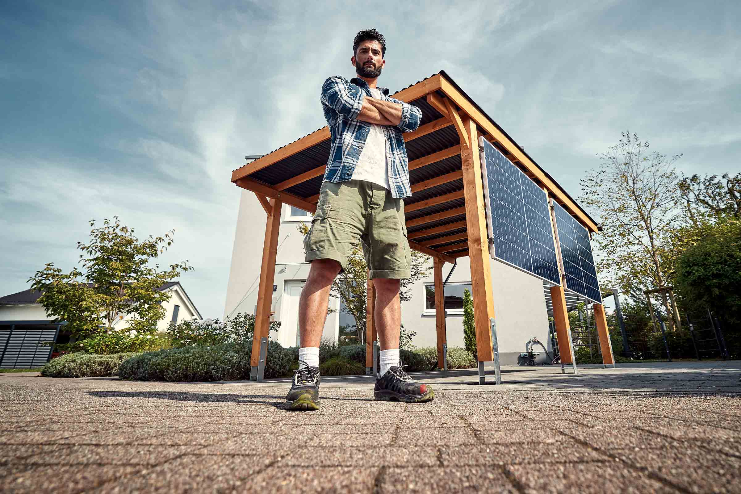 Man met gekruiste armen voor een carport met zonnepanelen