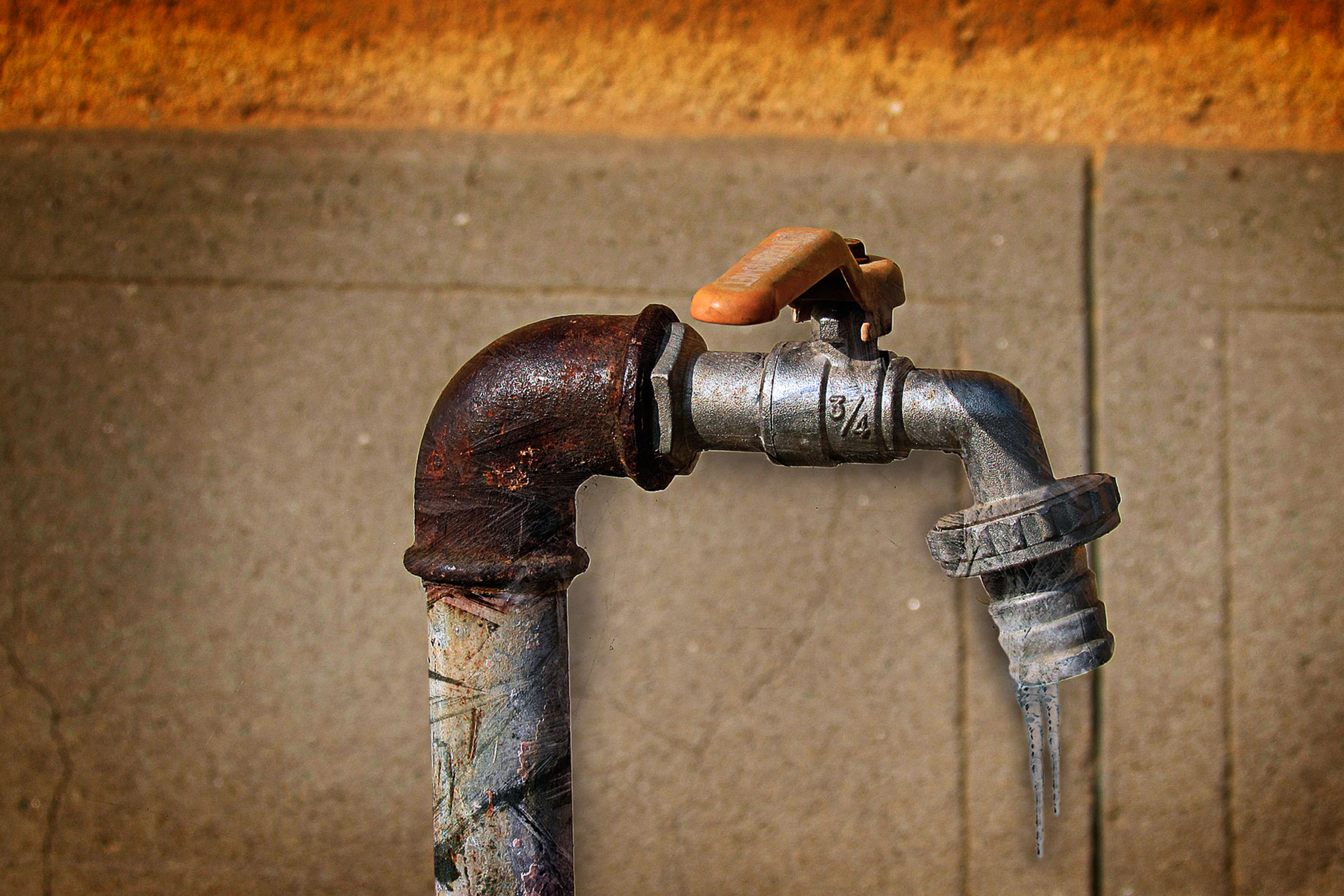 Een metalen waterkraan met roest en ijspegels