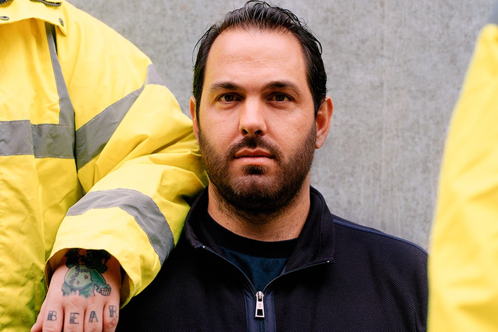 Portret van een man met een baard die een werkkledingjas draagt