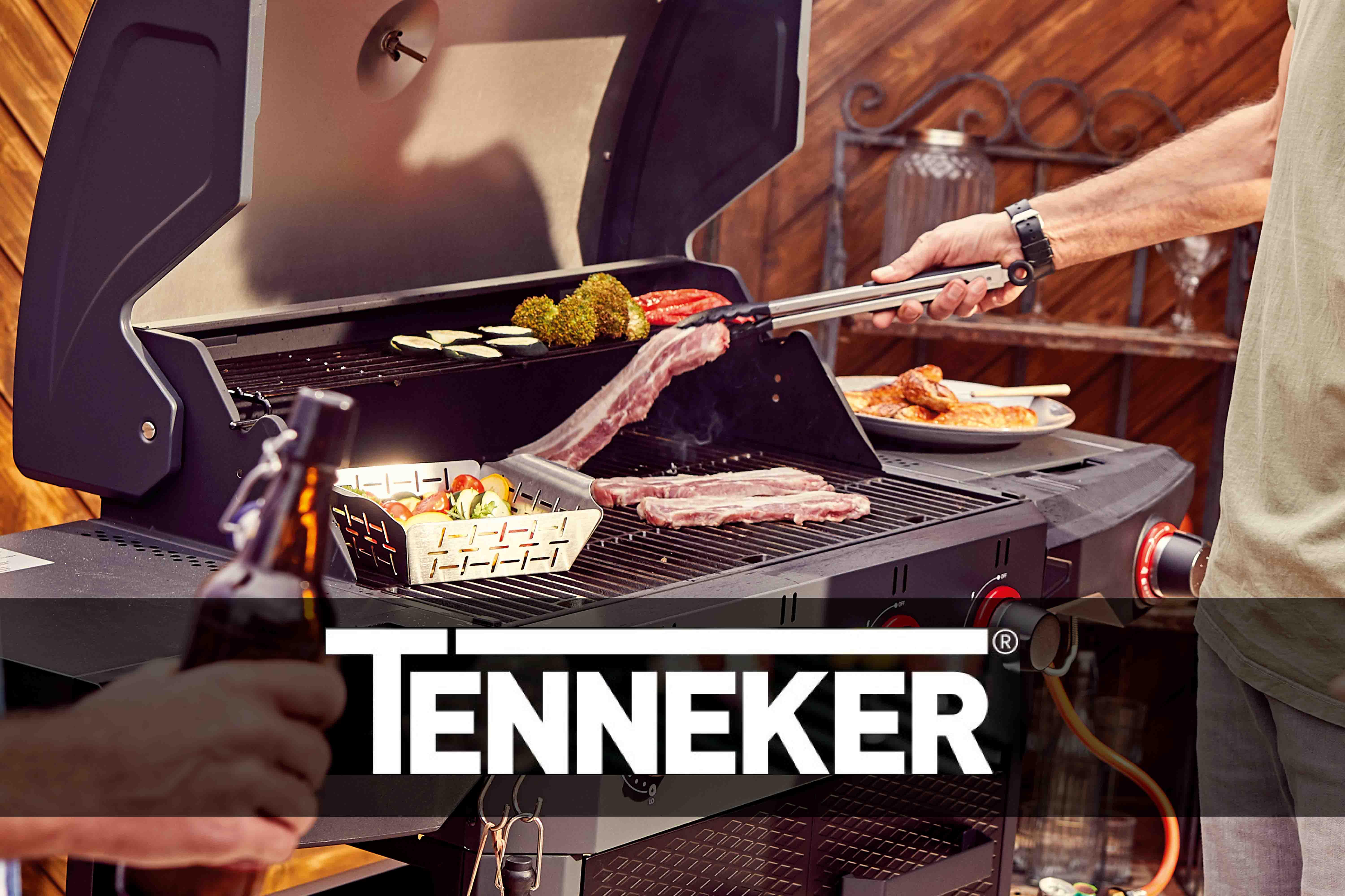 Tenneker barbecue met gegrild voedsel en barbecuetang.