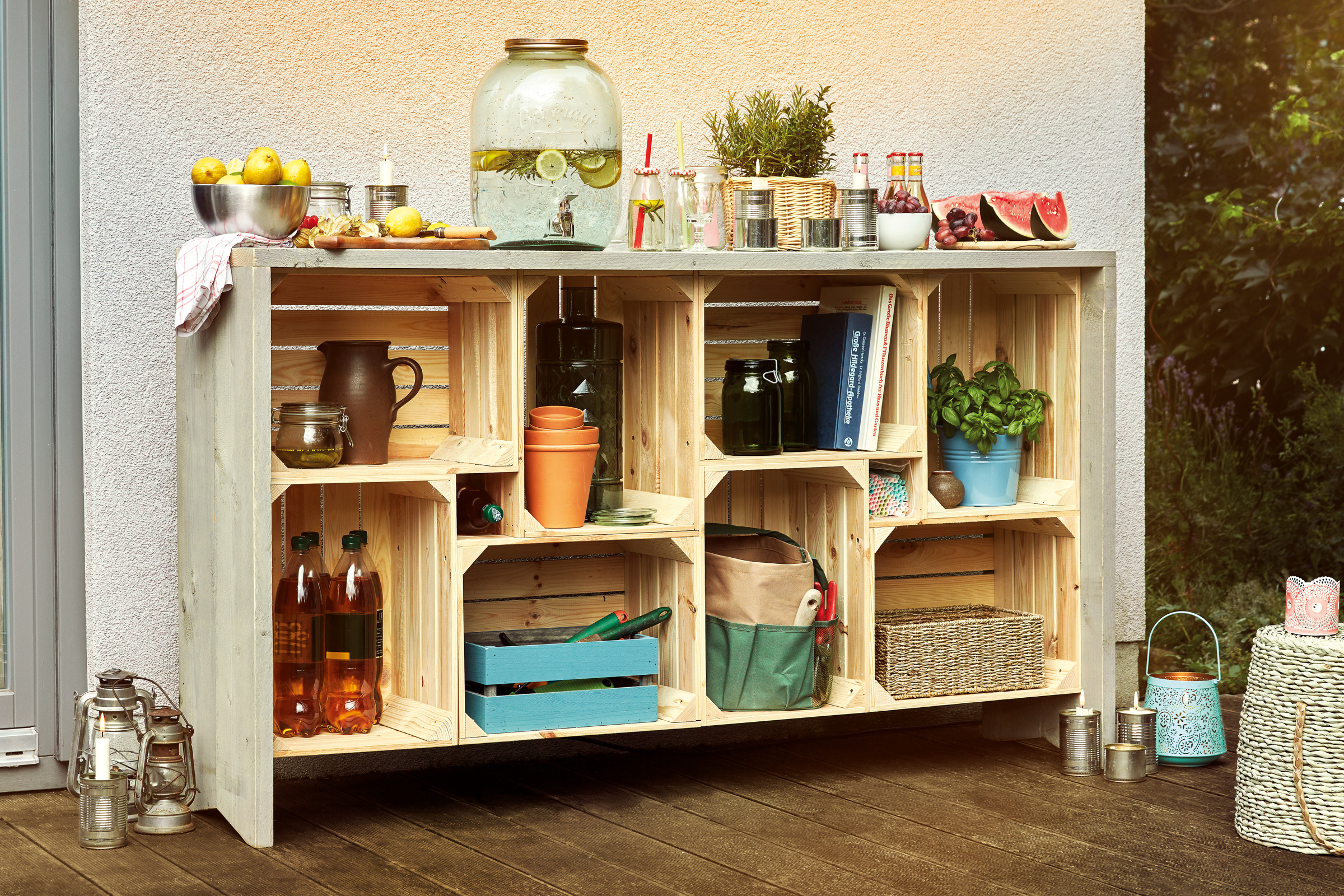 Stellingkast van houten kisten gedecoreerd met drankjes, fruit, planten en tuingereedschap