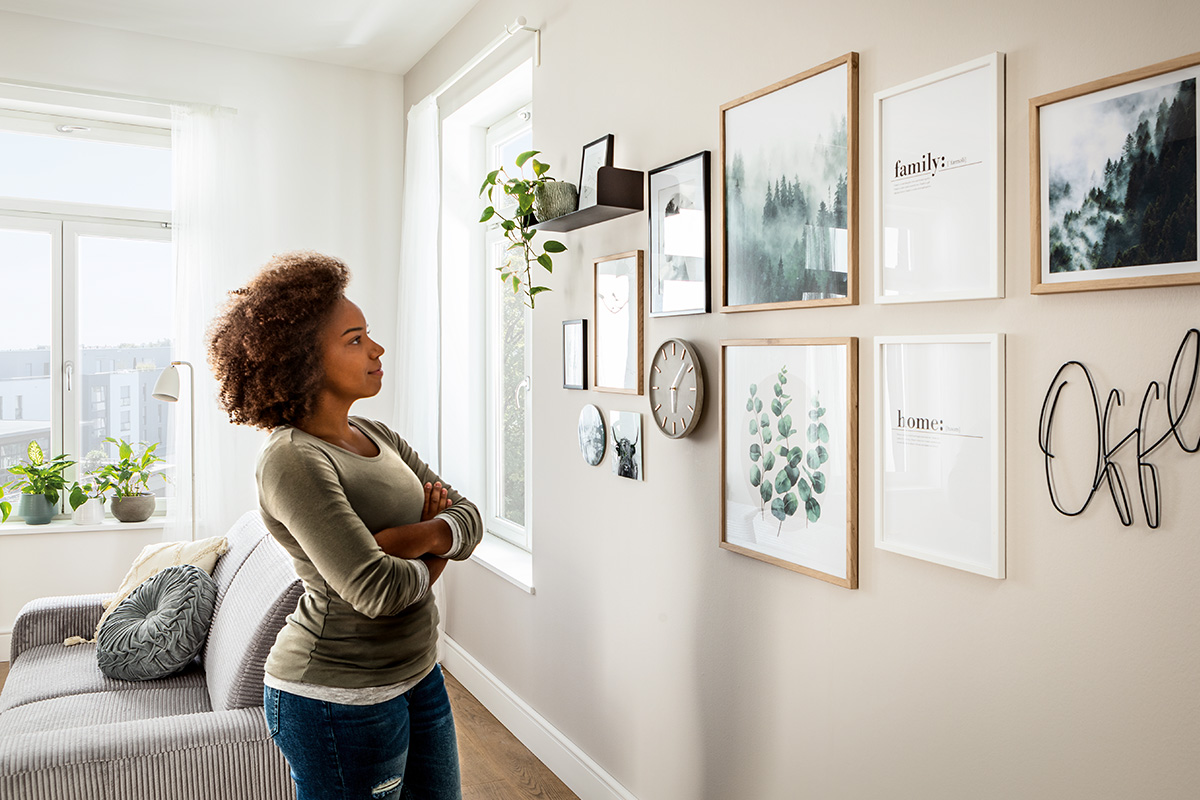 Vrouw bekijkt fotolijsten en wanddecoratie in de woonkamer