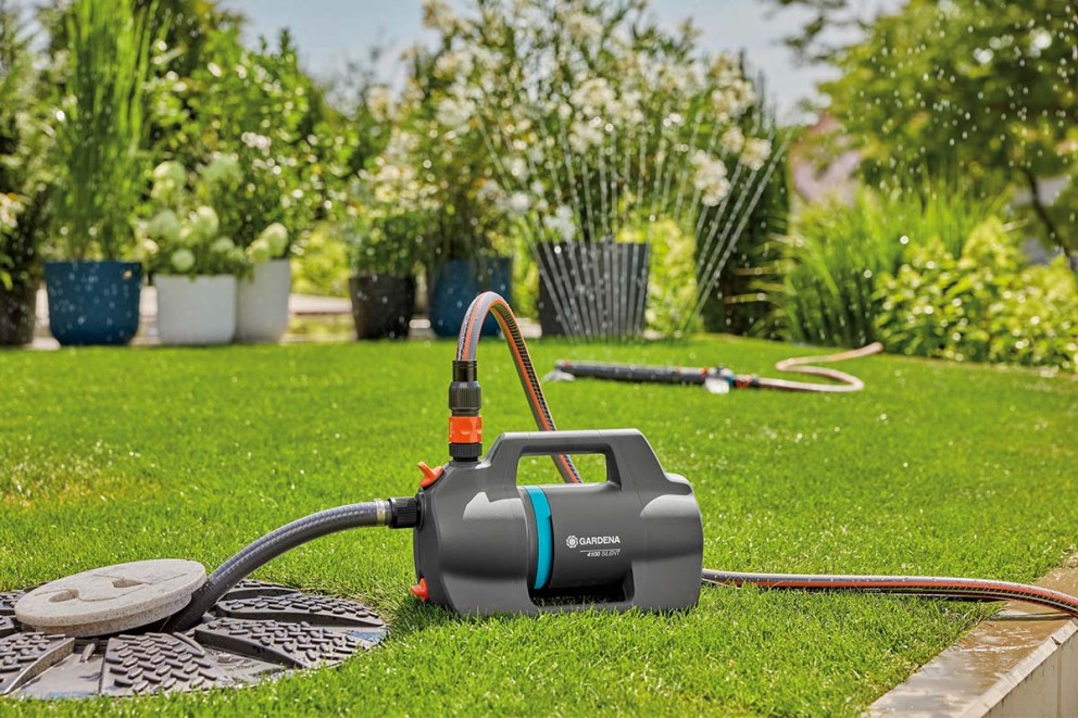Gardena tuinpomp op gazon met bewatering op de achtergrond