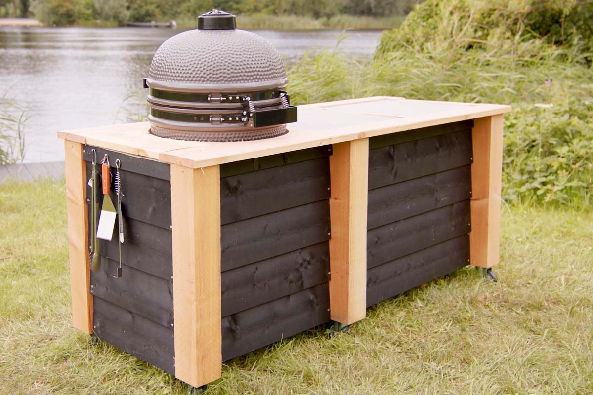 Keramische grill op onderkast met gereedschap in de tuin