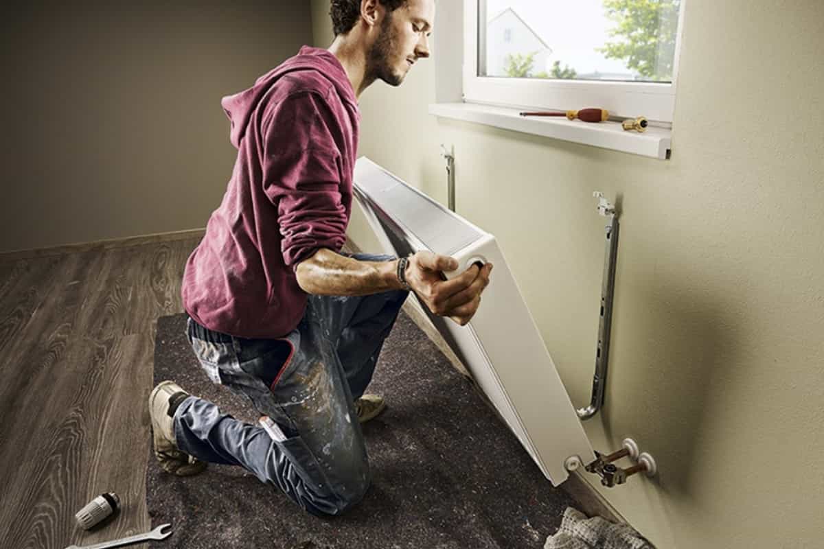 Ambachtsman installeert radiator in een kamer.