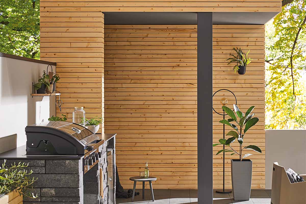 Scène van een buitenkeuken met barbecue, houten bekleding en decoratie