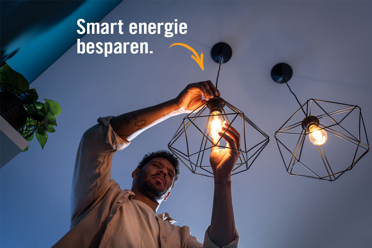 Man vervangt een gloeilamp in een geometrische hanglamp om slim energie te besparen.