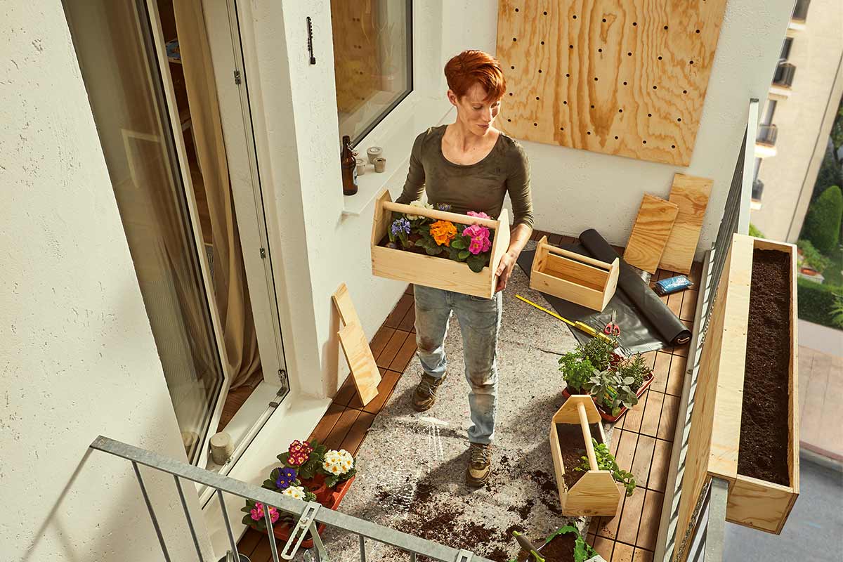 Vrouw op het balkon met houten plantenbakken en bloemen